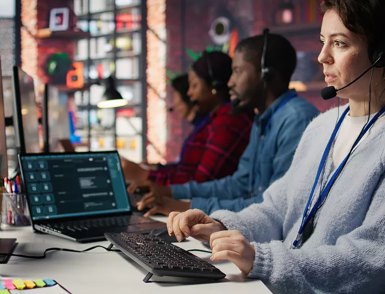 Diverse call centre team wearing headsets handling client service calls at workstations