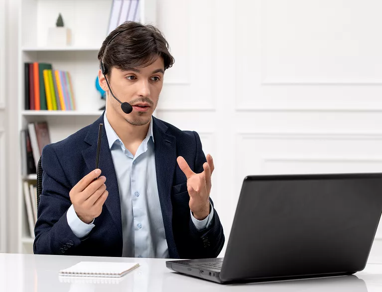 Male lead generation specialist wearing headset gesturing at laptop during client call